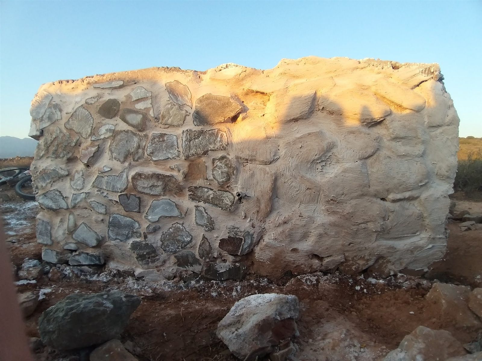 Riverside klipmuurtjie — stone packed by hand inside the shutter-board formwork before the pour